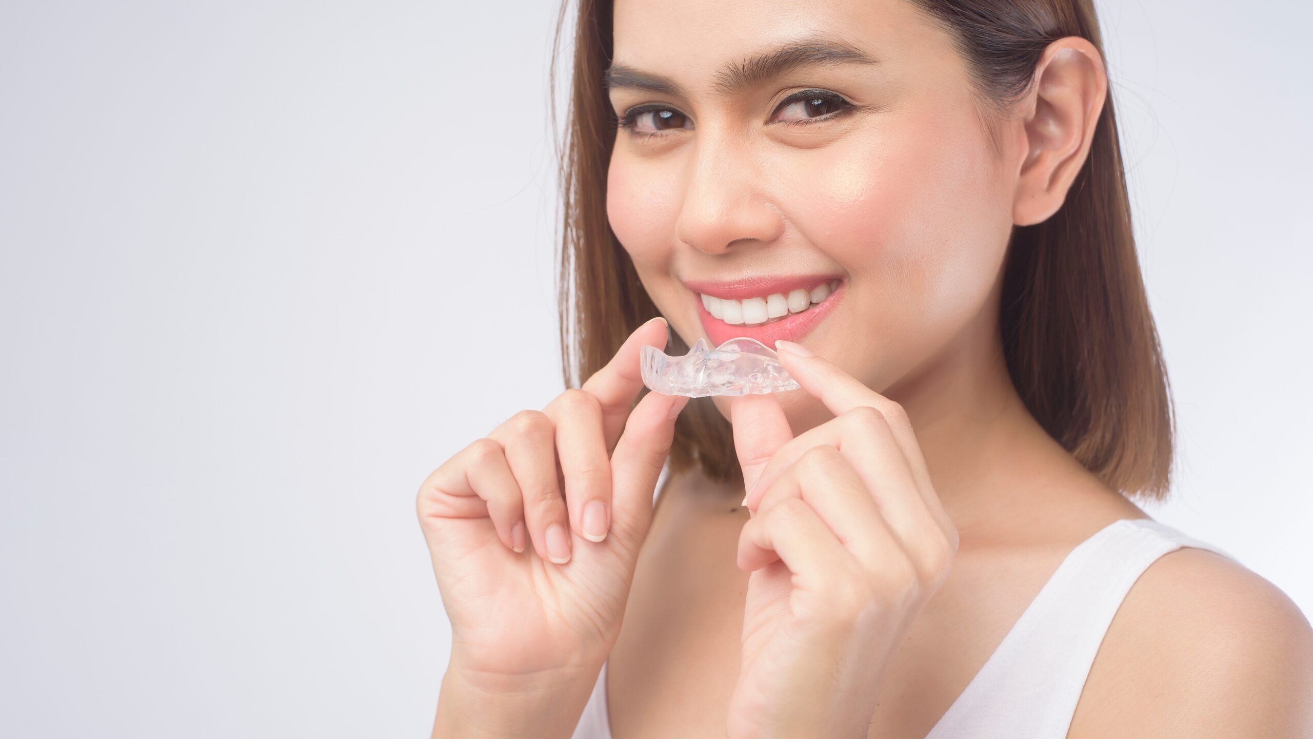 Une femme souriant avec des gouttières Invisalign, une solution d'orthodontie invisible